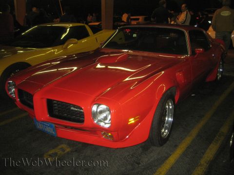 1968 Ford Mustang - A red Pontiac Firebird is parked in a lot at night, with a yellow car beside it.