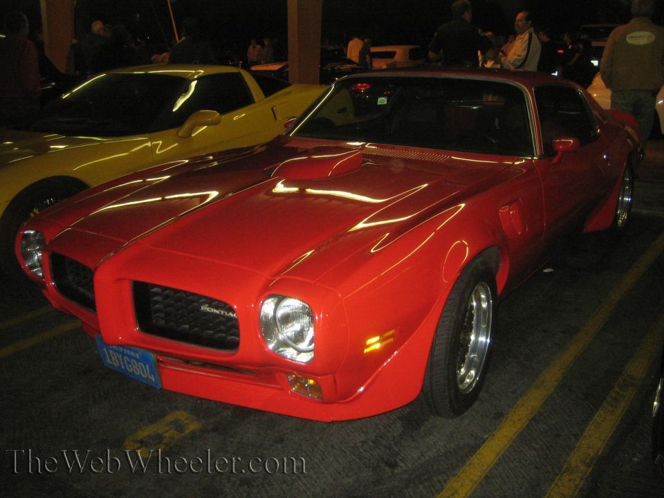 Red 1970s Pontiac Firebird parked next to a yellow car