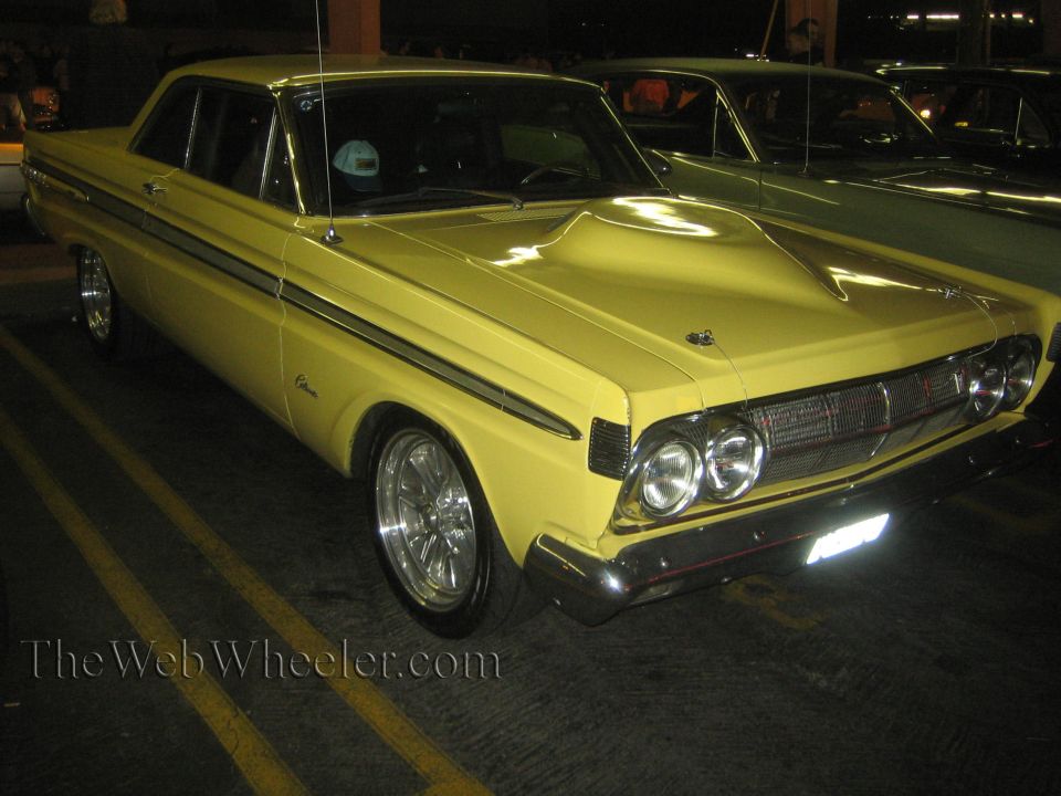 yellow 1964 Mercury Comet with a prominent hood scoop, parked next to another car