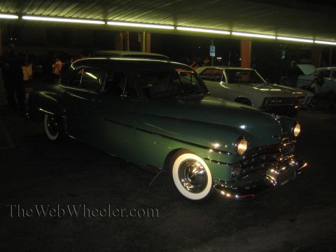1968 Ford Mustang - A green sedan with whitewall tires is parked under lights at night, with another vehicle behind it.
