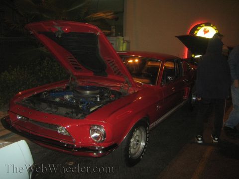 1968 Ford Mustang - A red 1967-1968 Ford Mustang is parked with its hood open, revealing the engine bay.