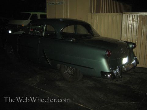 1968 Ford Mustang - Rear view of a green coupe parked outdoors at night, with a white van visible in the background.