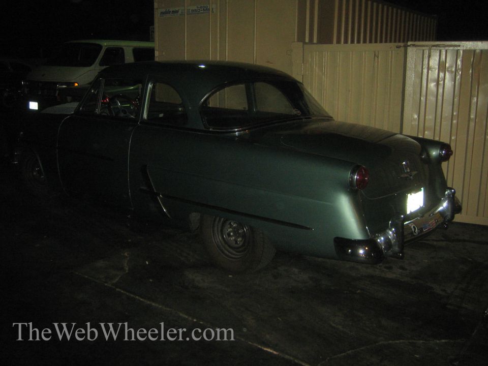 Green coupe rear view at night
