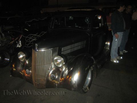 1968 Ford Mustang - A dark hot rod with chrome accents and flame decals is parked at night.