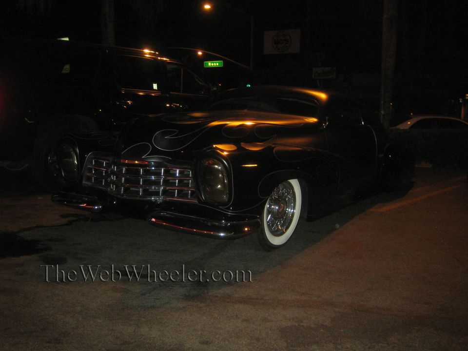 black hot rod with silver flames, wide whitewall tires, and chrome grille