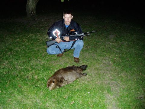 1995 Mercury Grand Marquis - A man poses with a rifle next to a deceased beaver on a grassy area at night.