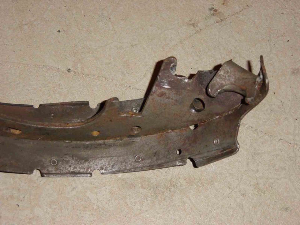 Rusty curved sheet-metal bumper or valance bracket lying on concrete floor