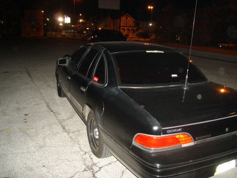 1992 Ford Crown Victoria - A black 1992 Ford Crown Victoria is parked at night, viewed from the rear quarter panel.