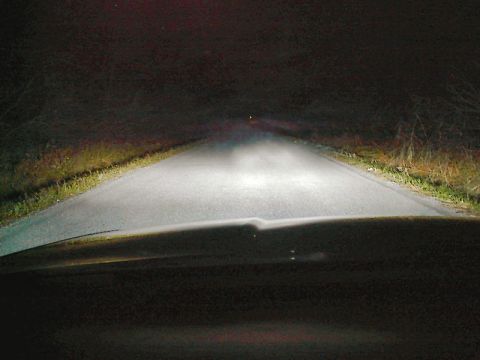 1985 Mercury Grand Marquis - Headlights cut through the darkness on a rural road at night. Supermotors.net logo is visible.