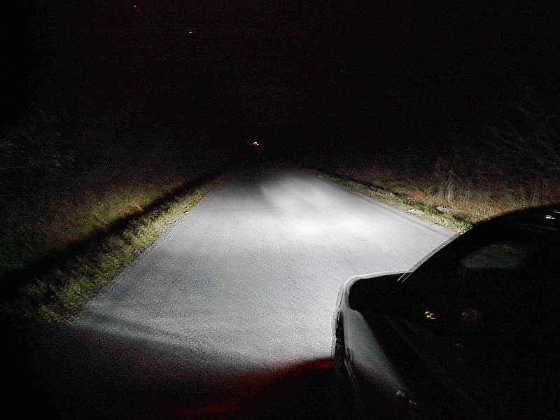 Car driving on a dark road with headlights on