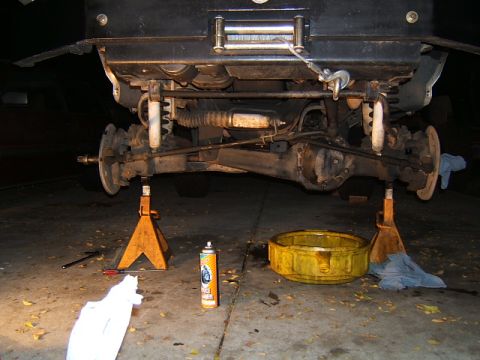1988 Ford Bronco - Undercarriage of a vehicle on jack stands, with suspension and differential exposed for maintenance.