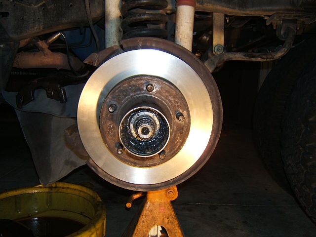 Front brake rotor and hub exposed on a vehicle raised on a jack stand