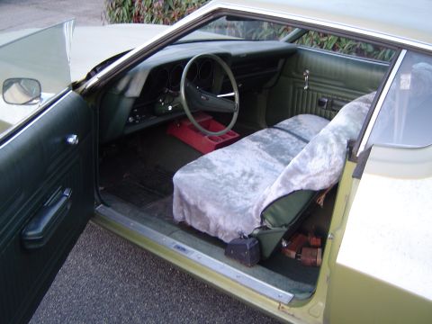 1973 Ford Torino - The interior of a vintage car shows a bench seat with a fuzzy cover and a green dashboard.