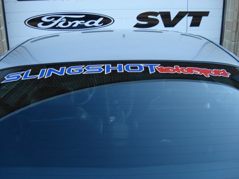 1998 Ford Taurus - A car with a motorsport banner is parked in front of a garage door displaying the Ford SVT logo.