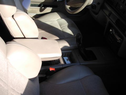 1995 Ford Taurus - Interior view of a 1995 Ford Taurus, showing the beige seats, armrest, and center console with gear shifter.