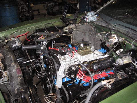 1973 Ford Ranchero - The engine bay of a car is shown with a V8 engine, carburetor, and many wires and hoses.