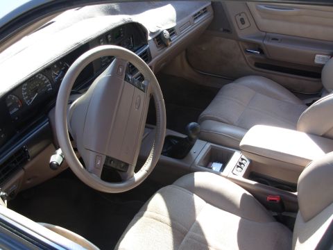 1995 Ford Taurus - The interior of a car features tan seats, a tan dashboard, and a center console with a gear shifter.