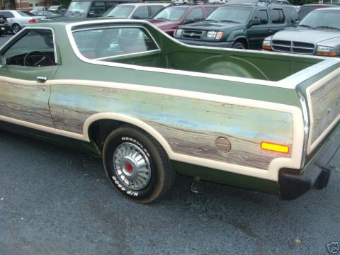 1973 Ford Ranchero - A green pickup truck with wood paneling is parked in a lot, with other vehicles visible in the background.