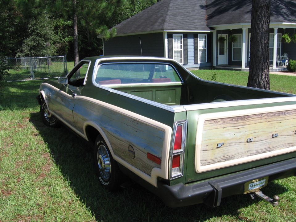 Green 1973 Ford Ranchero with wood paneling on the tailgate and sides, parked on grass