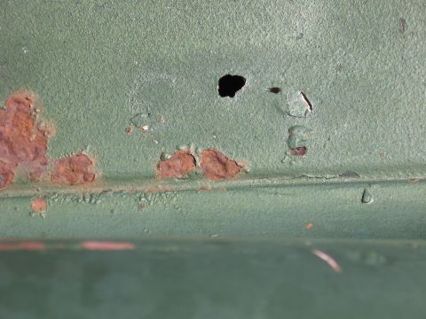 1973 Ford Ranchero - This close-up shows significant rust damage and a hole in a painted metal surface.