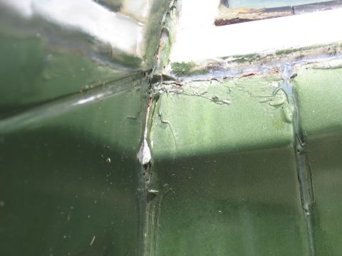 1973 Ford Ranchero - Close-up of a green vehicle's corner shows damage and wear around a window seal.