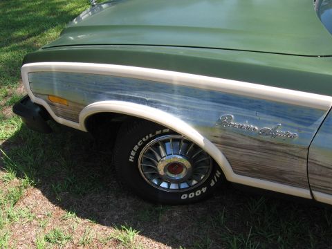 1973 Ford Ranchero - Close-up of a 1973 Ford Ranchero Squire's front fender, showing its distinctive wood grain paneling and chrome accents.