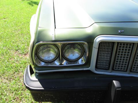 1973 Ford Ranchero - Close-up of the front of a green 1972 Ford Ranchero, focusing on the headlights and grille detail.