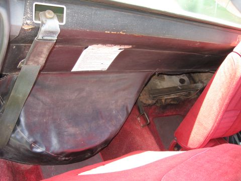 1973 Ford Ranchero - The interior of a vehicle shows a seatbelt, a dark dash cover, and red carpeting.