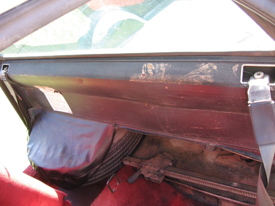Spare tire and jack visible in the trunk of a car, next to a red seat