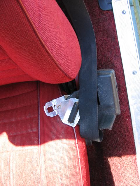 1973 Ford Ranchero - Close-up of a vehicle's interior, focusing on the seatbelt and red upholstery.