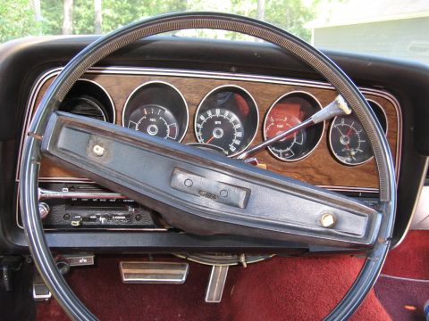 1973 Ford Ranchero - The interior of a 1973 Ford Ranchero shows a woodgrain dashboard with four circular gauges and a black steering wheel.