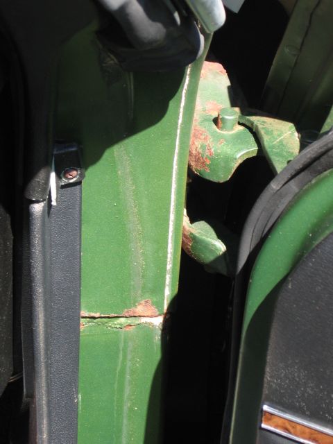 1973 Ford Ranchero - The door jamb of a green vehicle shows signs of rust around the hinge mounting points.