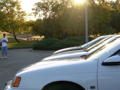 1995 Ford Taurus - A white sedan is parked in a lot with a person in the background.