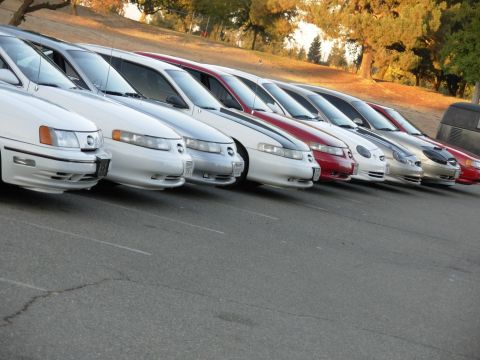 1995 Ford Taurus - A row of Ford Taurus sedans, including white and red models, are parked in a lot during the day.
