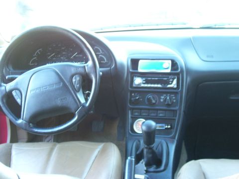 1997 Ford Probe - The interior of a car is visible, the steering wheel, dashboard, and center console with various controls and a radio.
