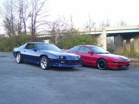 1997 Ford Probe - A red 1997 Ford Probe and a blue Chevrolet Camaro are parked outdoors under an overpass.