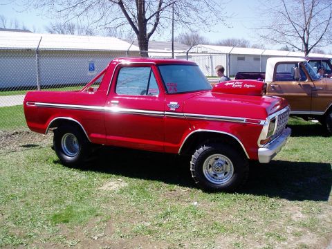 1986 Ford Bronco - This red Ford Bronco features a prominent hood scoop and is parked next to another Ford truck.