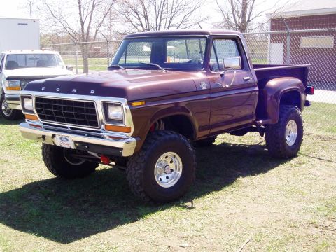 1986 Ford Bronco - This lifted 1979 Ford pickup truck is parked on grass with another white truck in the background.
