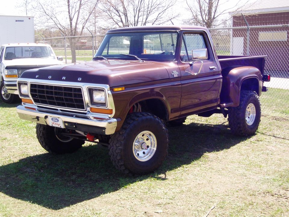 Brown 1979 Ford pickup truck with lifted suspension and chrome wheels. Another white truck is visible behind it