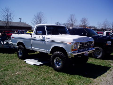 1986 Ford Bronco - A lifted white 1979 Ford pickup truck is parked on grass with its hood removed, next to a black truck.