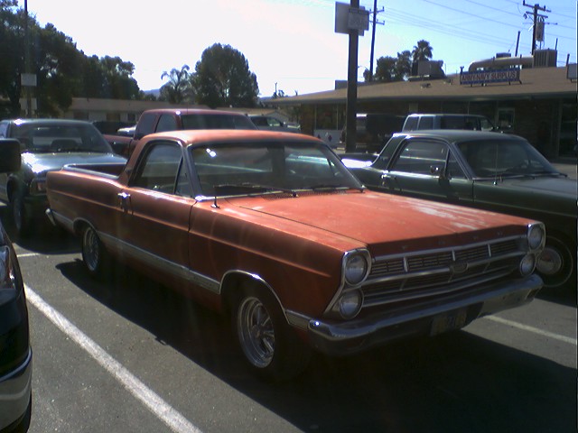 Orange Ford Ranchero parked next to a green car