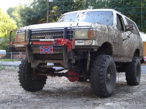 1989 Ford Bronco - This heavily modified Ford Bronco is covered in mud, suggesting recent off-road use.