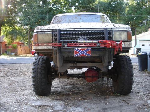 1989 Ford Bronco - This heavily modified pickup truck is covered in mud and features oversized tires and a winch on the front bumper.