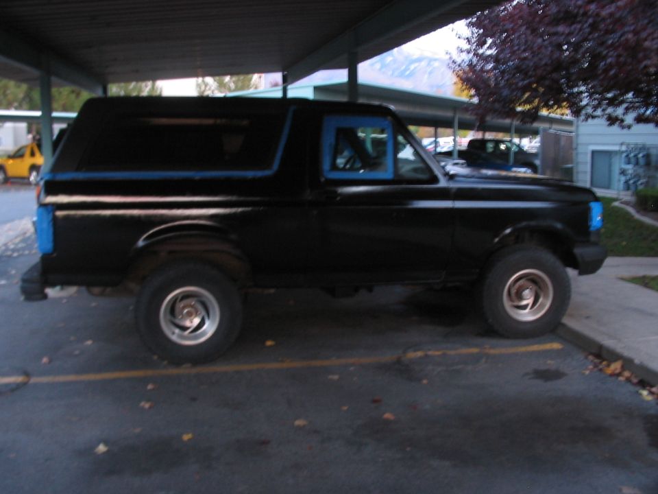Side view of a black 1991 Ford Bronco with blue trim