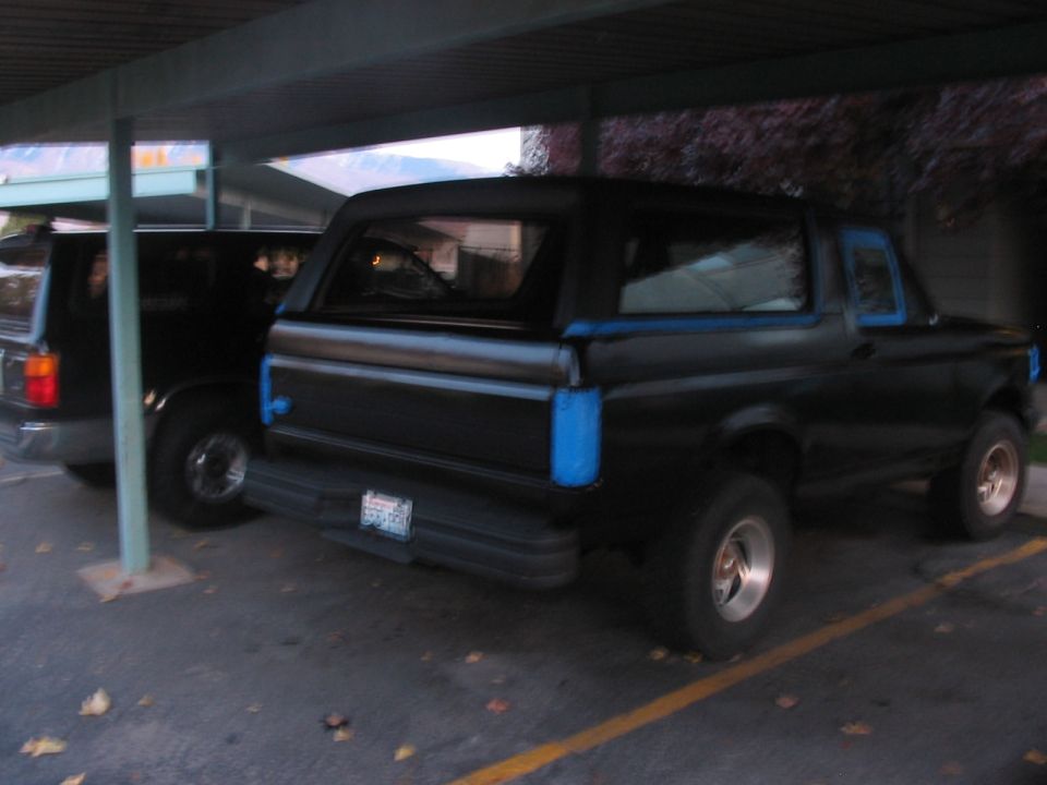 1991 Ford Bronco parked under a carport next to another SUV