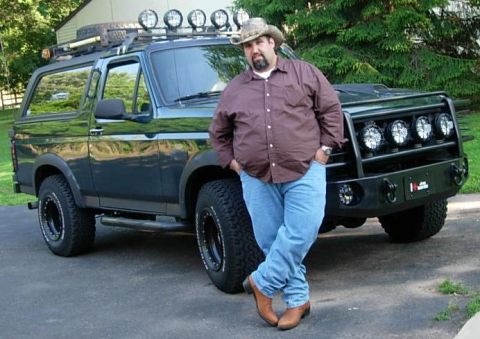 1993 Ford Bronco - A man poses with his modified 1993 Ford Bronco, a heavy-duty front bumper and multiple roof-mounted lights.
