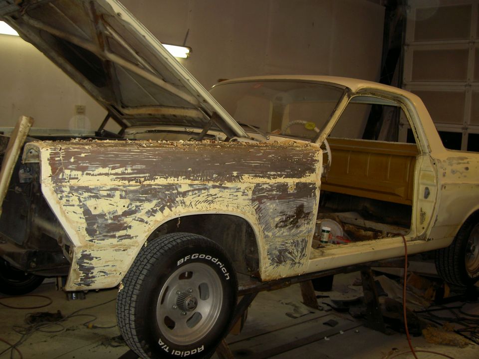 Old pickup with stripped paint and BFGoodrich tire in a garage