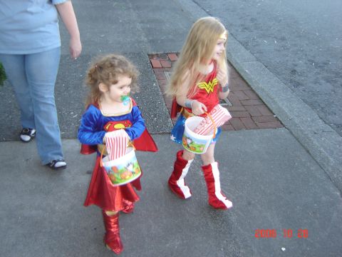 1993 Ford Bronco - Two young trick-or-treaters, dressed as Superman and Wonder Woman, walk down a sidewalk with their candy buckets.