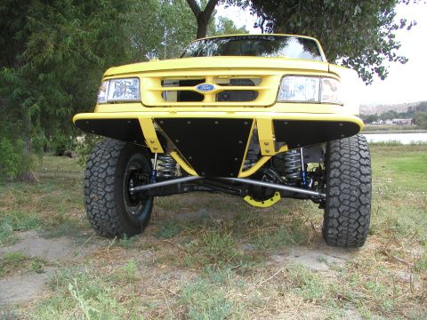 1984 Ford Bronco - Front view of a modified yellow truck, showing its suspension and bumper.