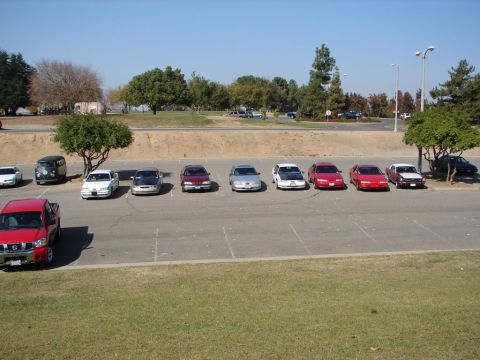 1992 Ford Taurus - A variety of sedans and a pickup truck are parked in an outdoor lot on a sunny day.